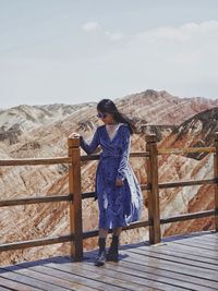 Full length of woman standing on railing against sky