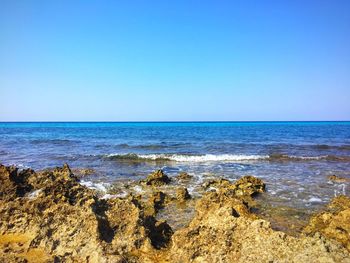 Scenic view of beach against clear blue sky