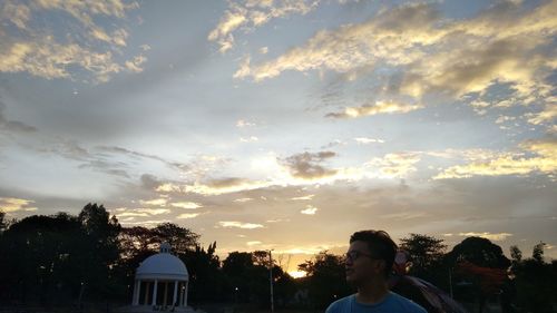 Silhouette people by building against sky during sunset