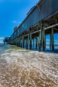 Pier on beach by sea against sky