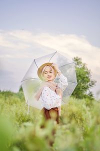 Woman with umbrella standing against plants