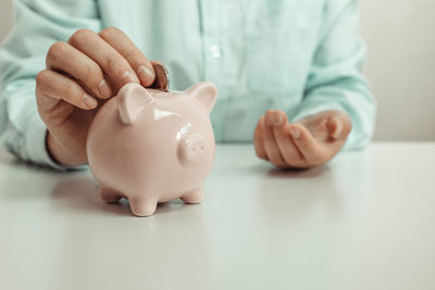 Midsection of man with piggy bank on table