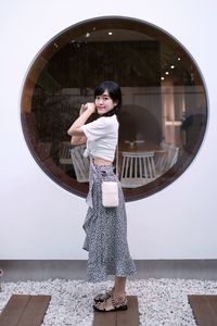 Portrait of young woman standing against wall