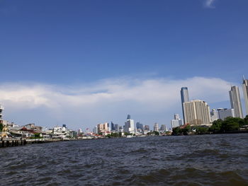 Sea by buildings against sky in city