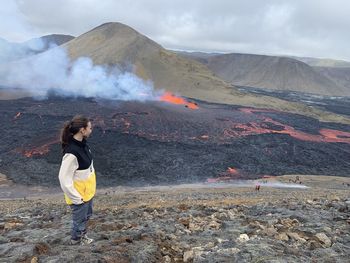 Rear view of woman standing on the background of erupting volcano 