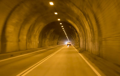Cars on road in illuminated tunnel