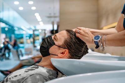 Man with mask getting his hair washed at hair salon