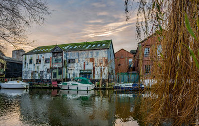 Buildings by canal against sky