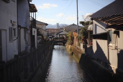 Canal amidst houses against sky in city