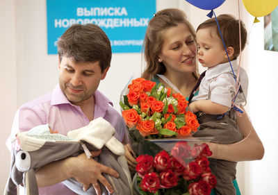 Smiling family with newborn baby standing at hospital
