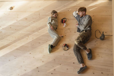 Father and daughter have rest, lying after sanding the floor in an eco house. top view, time together