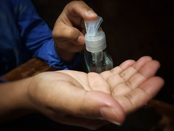 Close-up of man holding glass bottle with water