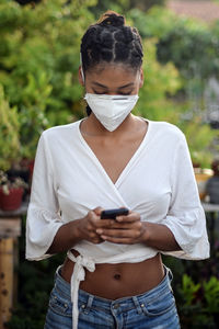 Young black woman in face mask using a smartphone