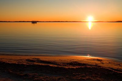 Smooth lake level at warm colorful sunset, sandy beach in bay