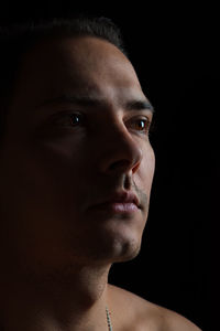 Close-up portrait of young man against black background