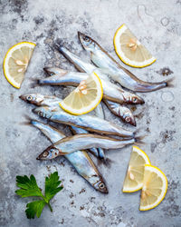 High angle view of raw fish with lemon slices on table