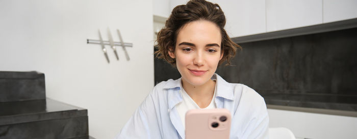 Portrait of smiling young woman using mobile phone