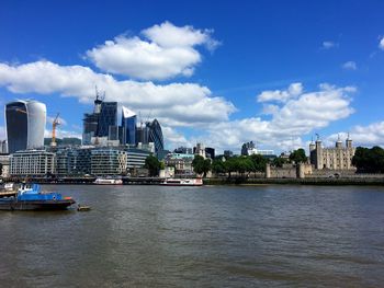 View of buildings by river against cloudy sky