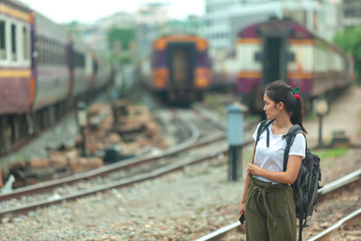 Full length of young woman standing on railroad track