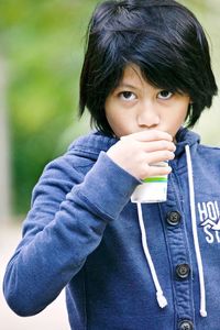 Portrait of boy drinking from glass outdoors