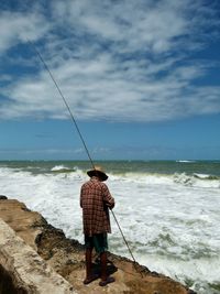 Rear view of fisherman fishing in sea