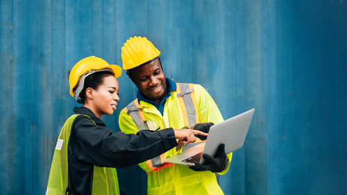 Engineers using laptop while standing in factory