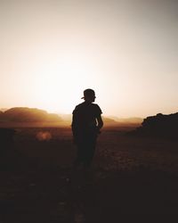 Silhouette man standing on desert against sky during sunset