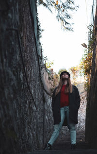 Full length portrait of young woman standing on tree trunk