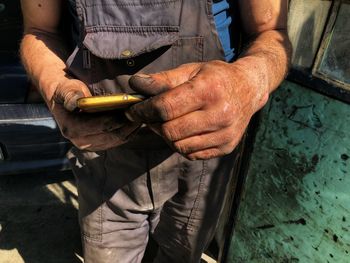 Midsection of mechanic using mobile phone