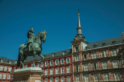 Low angle view of statue against building in city