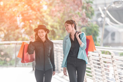 Happy friends with shopping bags walking on elevated walkway