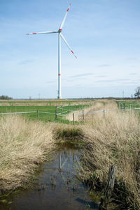 Windmills on field against clear sky