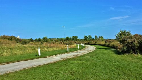 Road amidst field against sky