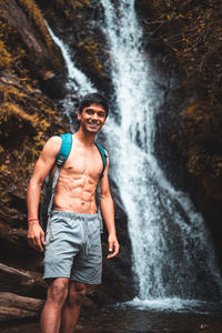 Full length of man standing against waterfall