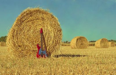 Guitar leaning against hay bale in field