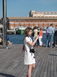 Woman photographing with mobile phone while standing outdoors