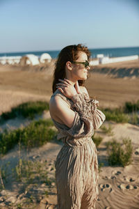 Portrait of young woman sitting on sand at beach