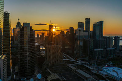 Modern buildings in city against sky during sunset