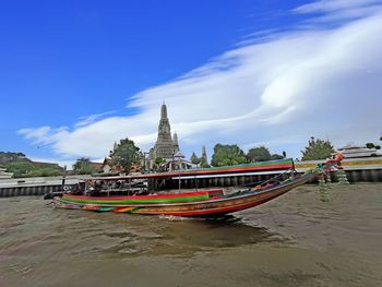 Boat moored in sea against cloudy sky