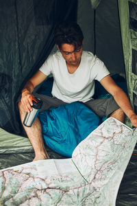 Young man looking at a map of mountain trails planning next trip on summer vacation