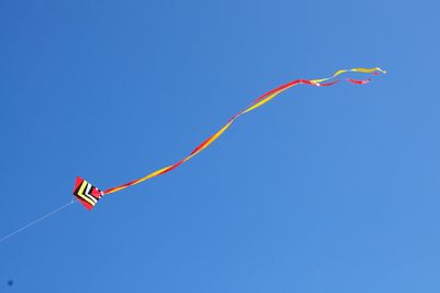 Low angle view of kite flying against clear blue sky