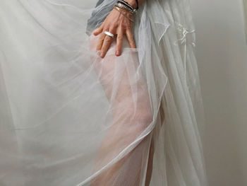 Midsection of bride standing by curtain