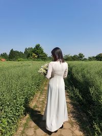 Rear view of woman standing on field against clear sky