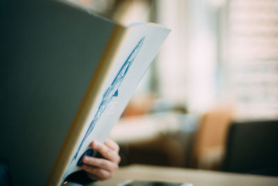 Cropped hand of woman reading book at office