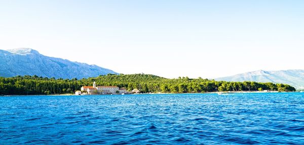 Panoramic view of sea by mountains against clear sky