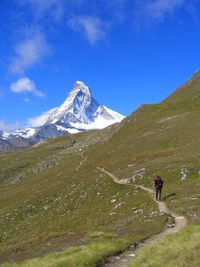 Man walking on mountain road against sky