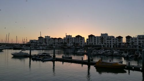 Boats moored in sea against sky during sunset