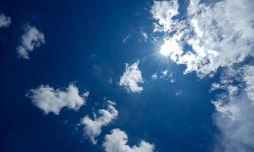 Low angle view of sunlight streaming through clouds