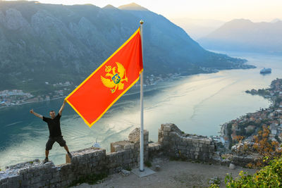 A man in shorts and a black t-shirt with the mountains in the sea bay as his backdrop