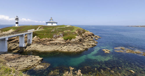 Lighthouse amidst sea and buildings against sky